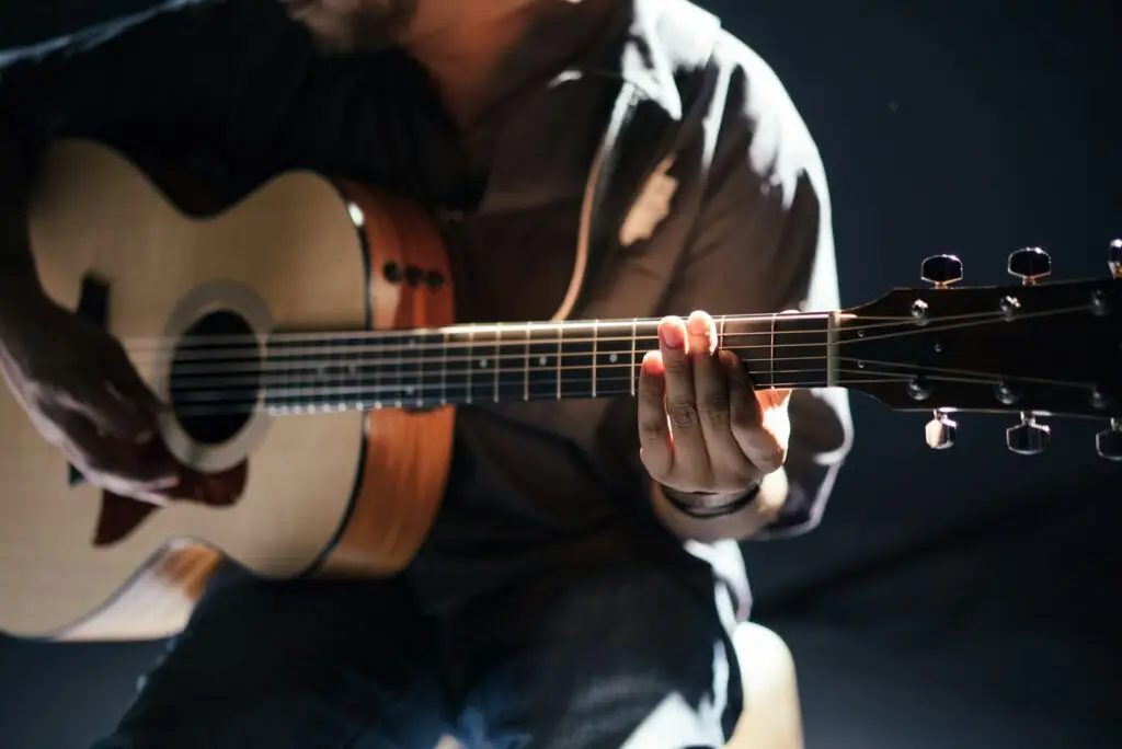 Manos de un músico tocando la guitarra en un espacio íntimo